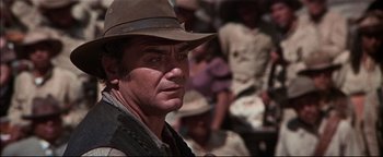 Movie still from “The Wild Bunch” (1969), directed by Sam Peckinpah – A man with a hat on looking into the distance; Close Up shot, Over the shoulder angle