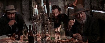 Movie still from “The Wild Bunch” (1969), directed by Sam Peckinpah – A man sitting at a table with a bunch of lit candles; Medium shot, Low angle
