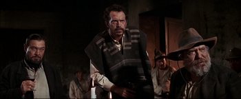 Movie still from “The Wild Bunch” (1969), directed by Sam Peckinpah – A man with a beard holding a gun in his hand; Medium shot, Low angle