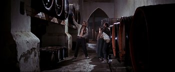 Movie still from “The Wild Bunch” (1969), directed by Sam Peckinpah – A group of people standing in a room with wine barrels; Wide shot, Low angle