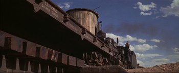 Movie still from “The Wild Bunch” (1969), directed by Sam Peckinpah – An old steam train is parked on the train tracks; Wide shot, Low angle