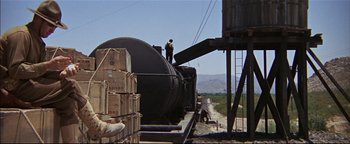 Movie still from “The Wild Bunch” (1969), directed by Sam Peckinpah – A man standing on the side of a train car; Extreme Wide shot, Low angle