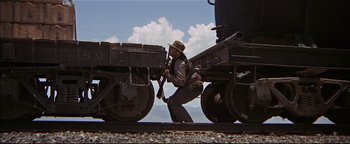 Movie still from “The Wild Bunch” (1969), directed by Sam Peckinpah – A man in a hat is standing on a train car; Wide shot, Low angle