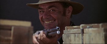 Movie still from “The Wild Bunch” (1969), directed by Sam Peckinpah – A man with a hat holding a gun in his hand; Close Up shot, Low angle