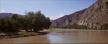 Movie still from “The Wild Bunch” (1969), directed by Sam Peckinpah – A body of water surrounded by mountains and trees; Extreme Wide shot, High angle