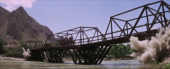 Movie still from “The Wild Bunch” (1969), directed by Sam Peckinpah – A group of people riding on a bridge over a river; Extreme Wide shot, High angle