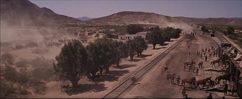 Movie still from “The Wild Bunch” (1969), directed by Sam Peckinpah – A train tracks running through a desert area; Extreme Wide shot, High angle