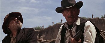 Movie still from “The Wild Bunch” (1969), directed by Sam Peckinpah – An older man wearing a hat sitting on top of a hill; Close Up shot, Low angle