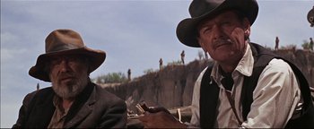 Movie still from “The Wild Bunch” (1969), directed by Sam Peckinpah – Two men in hats and vests sitting next to each other on a hill; Close Up shot, Low angle