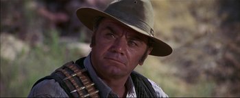 Movie still from “The Wild Bunch” (1969), directed by Sam Peckinpah – A man with a hat and a gun in his hand; Close Up shot, Over the shoulder angle