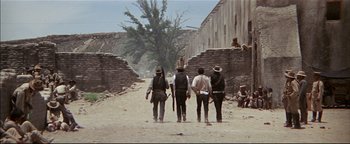 Movie still from “The Wild Bunch” (1969), directed by Sam Peckinpah – A group of men standing next to each other on a dirt road; Wide shot, Low angle