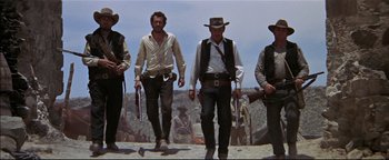 Movie still from “The Wild Bunch” (1969), directed by Sam Peckinpah – A group of men standing next to each other holding guns; Wide shot, Low angle