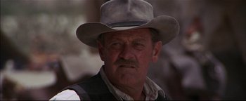 Movie still from “The Wild Bunch” (1969), directed by Sam Peckinpah – An older man wearing a cowboy hat and vest; Close Up shot, Over the shoulder angle