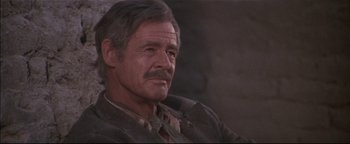 Movie still from “The Wild Bunch” (1969), directed by Sam Peckinpah – An older man sitting in a chair looking at the camera; Close Up shot, Low angle