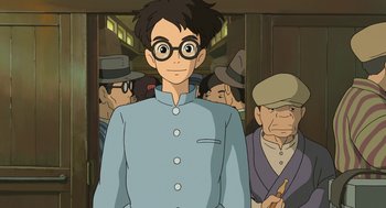 Movie still from “The Wind Rises” (2013), directed by Hayao Miyazaki – A man with glasses standing in front of a group of people; Medium shot, Low angle