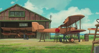 Movie still from “The Wind Rises” (2013), directed by Hayao Miyazaki – An old fashioned airplane parked in front of a barn; Extreme Wide shot, Low angle