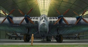 Movie still from “The Wind Rises” (2013), directed by Hayao Miyazaki – An airplane with propellors in a hangar with a man standing next to it; Extreme Wide shot, Low angle