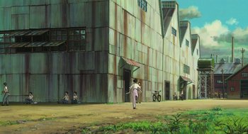 Movie still from “The Wind Rises” (2013), directed by Hayao Miyazaki – A man walking down a street near a large building; Extreme Wide shot, Low angle