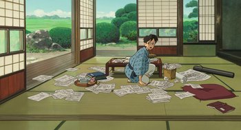 Movie still from “The Wind Rises” (2013), directed by Hayao Miyazaki – An animated scene of a man sitting on the floor with papers; Wide shot, High angle