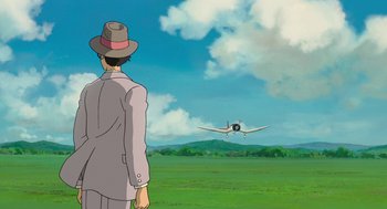 Movie still from “The Wind Rises” (2013), directed by Hayao Miyazaki – A man standing in front of an airplane in a field; Wide shot, Over the shoulder angle
