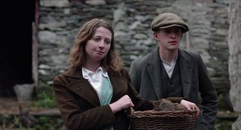 Movie still from “The Wind that Shakes the Barley” (2006), directed by Ken Loach – A man and a woman standing next to each other holding a basket; Medium shot, Low angle