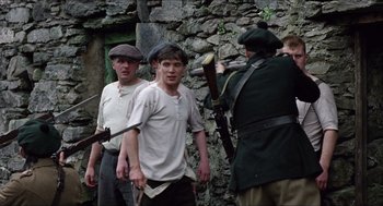 Movie still from “The Wind that Shakes the Barley” (2006), directed by Ken Loach – A group of men standing next to each other holding guns; Medium shot, Over the shoulder angle