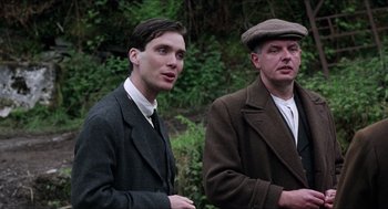 Movie still from “The Wind that Shakes the Barley” (2006), directed by Ken Loach – A man and a man standing next to each other; Medium shot, Low angle
