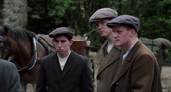 Movie still from “The Wind that Shakes the Barley” (2006), directed by Ken Loach – A group of young men standing next to each other on a street; Medium shot, Low angle
