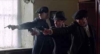 Movie still from “The Wind that Shakes the Barley” (2006), directed by Ken Loach – A group of men holding guns in a room; Medium shot, Low angle