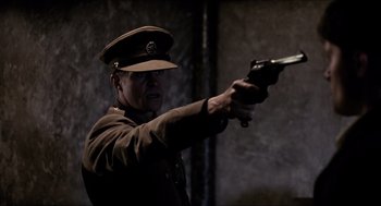 Movie still from “The Wind that Shakes the Barley” (2006), directed by Ken Loach – A man in a military uniform holding a gun; Medium shot, Low angle