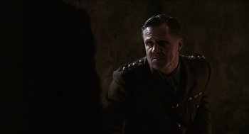 Movie still from “The Wind that Shakes the Barley” (2006), directed by Ken Loach – A man in military uniform sitting in front of a wall; Close Up shot, Over the shoulder angle
