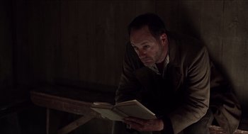 Movie still from “The Wind that Shakes the Barley” (2006), directed by Ken Loach – A man is reading a book in a dark room; Medium shot, Low angle