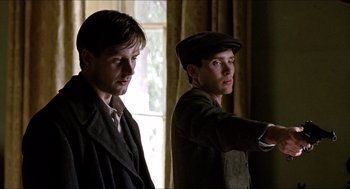 Movie still from “The Wind that Shakes the Barley” (2006), directed by Ken Loach – Two men are standing in front of a window and one is pointing; Close Up shot, Low angle