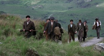 Movie still from “The Wind that Shakes the Barley” (2006), directed by Ken Loach – A group of men walking up a hill with guns; Wide shot, High angle