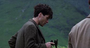 Movie still from “The Wind that Shakes the Barley” (2006), directed by Ken Loach – A man holding a camera in his hands; Close Up shot, Over the shoulder angle