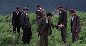 Movie still from “The Wind that Shakes the Barley” (2006), directed by Ken Loach – A group of men standing in the grass; Wide shot, Over the shoulder angle