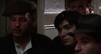 Movie still from “The Wind that Shakes the Barley” (2006), directed by Ken Loach – A man in a hat and jacket looking into the distance; Close Up shot, Over the shoulder angle