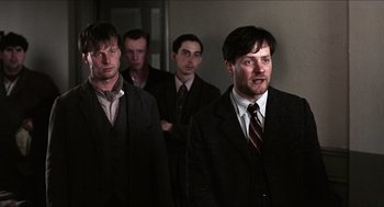Movie still from “The Wind that Shakes the Barley” (2006), directed by Ken Loach – A group of men standing next to each other in suits; Medium shot, Low angle
