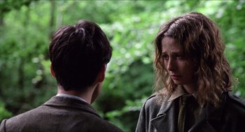 Movie still from “The Wind that Shakes the Barley” (2006), directed by Ken Loach – A man and a woman standing next to each other in a forest; Close Up shot, Over the shoulder angle