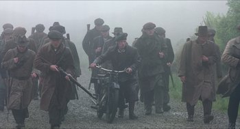 Movie still from “The Wind that Shakes the Barley” (2006), directed by Ken Loach – A group of men walking down a dirt road with a motorcycle; Wide shot, High angle