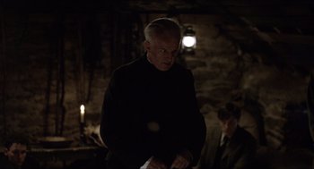 Movie still from “The Wind that Shakes the Barley” (2006), directed by Ken Loach – A man standing in the dark holding papers; Medium shot, Over the shoulder angle