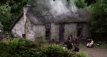 Movie still from “The Wind that Shakes the Barley” (2006), directed by Ken Loach – A group of people standing outside of an old house; Extreme Wide shot, Low angle