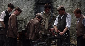 Movie still from “The Wind that Shakes the Barley” (2006), directed by Ken Loach – A group of men standing next to each other near a bicycle; Medium shot, High angle