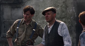 Movie still from “The Wind that Shakes the Barley” (2006), directed by Ken Loach – Two men standing next to each other in a forest; Medium shot, Low angle