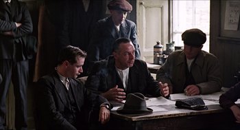 Movie still from “The Wind that Shakes the Barley” (2006), directed by Ken Loach – A group of men sitting at a table talking to each other; Medium shot, Over the shoulder angle