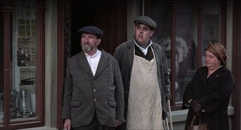Movie still from “The Wind that Shakes the Barley” (2006), directed by Ken Loach – A couple of men standing next to each other on a porch; Medium shot, Low angle