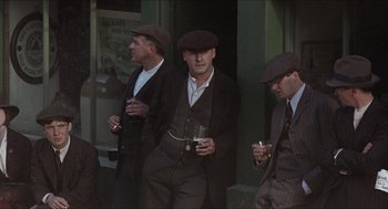Movie still from “The Wind that Shakes the Barley” (2006), directed by Ken Loach – A group of men standing next to each other holding drinks; Medium shot, Low angle