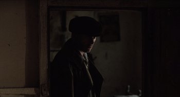 Movie still from “The Wind that Shakes the Barley” (2006), directed by Ken Loach – A man wearing a hat standing in the dark; Close Up shot, Over the shoulder angle