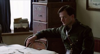 Movie still from “The Wind that Shakes the Barley” (2006), directed by Ken Loach – A man sitting at a table in a room; Medium shot, Low angle