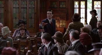 Movie still from “The Wind that Shakes the Barley” (2006), directed by Ken Loach – A man in a suit is talking to a group of people in a church; Medium shot, Low angle